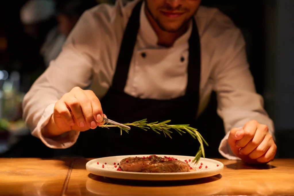 hand-of-young-male-chef-putting-aromatic-herb-on-t-2026-01-08-00-15-02-utc.webp