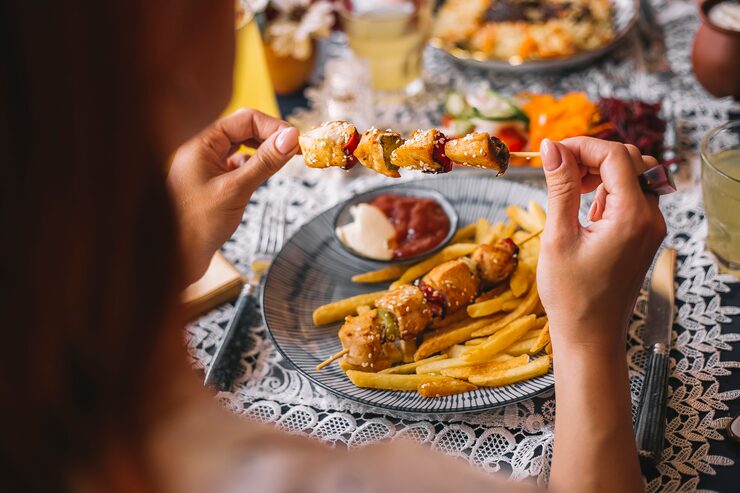 woman-holding-chicken-pieces-skewers-sprinkled-with-sesame_141793-2199